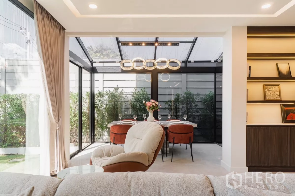 Detached House for rent or sale in Prawet, Bangkok - Living room opening to glass dining pavilion with illuminated shelves
