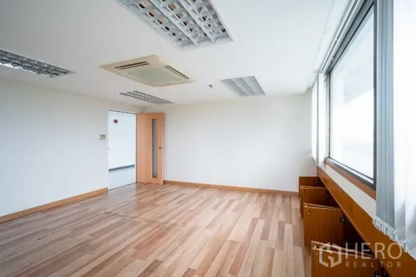 Office Space for rent in Pathum Wan, Bangkok - Corner office with wood laminate flooring, cassette air-conditioning, recessed lighting, and wide windows with built-in storage.