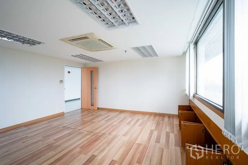 Office Space for rent in Pathum Wan, Bangkok - Corner office with wood laminate flooring, cassette air-conditioning, recessed lighting, and wide windows with built-in storage.