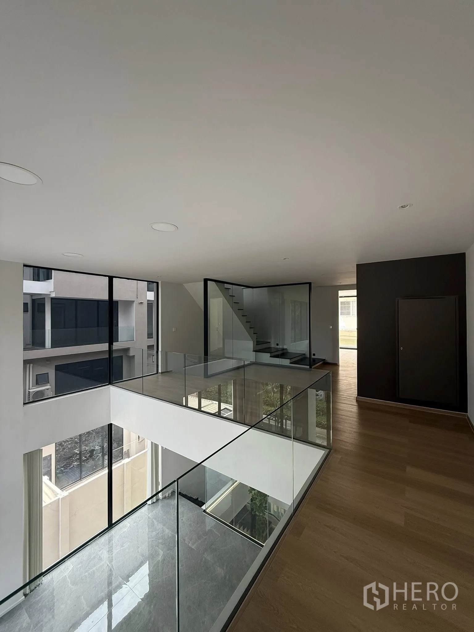 带办公室的家 出租或出售在Lat Phrao, Bangkok - 上层回廊，玻璃栏杆环绕中央天井与楼梯。