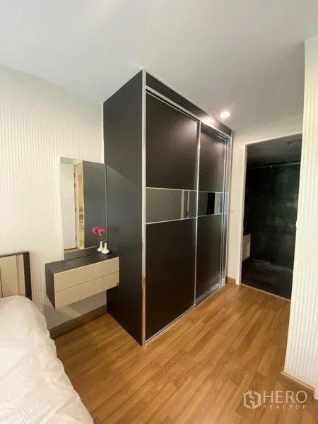 Condominium for rent in Watthana, Bangkok - Master bedroom with sleek black sliding wardrobe and access to an ensuite bathroom.