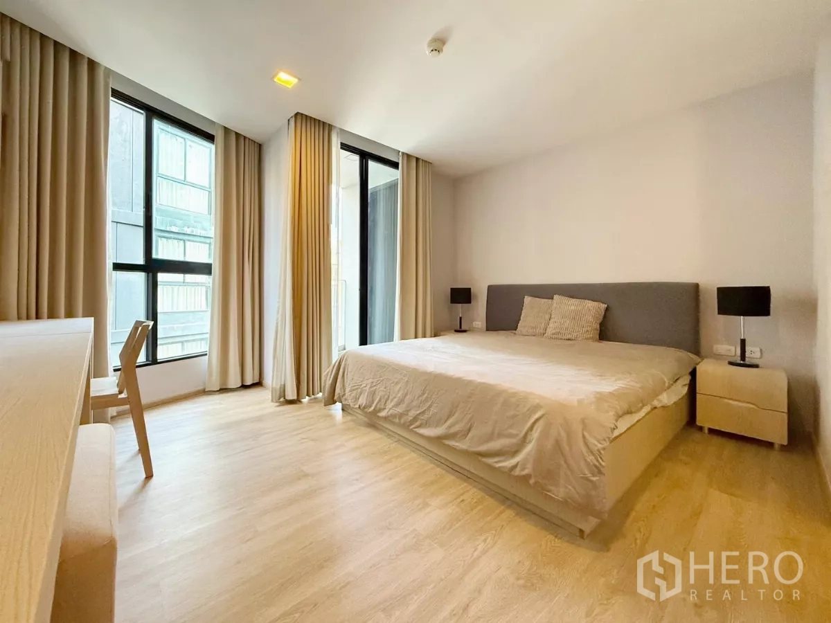 公寓 出租或出售在Watthana, Bangkok - 宽敞卧室，转角大窗与窗帘，摆放双人床。