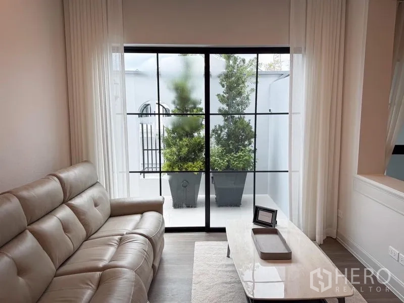 Detached House for rent or sale - Small lounge opening to a patio with potted trees behind black-frame sliding doors.