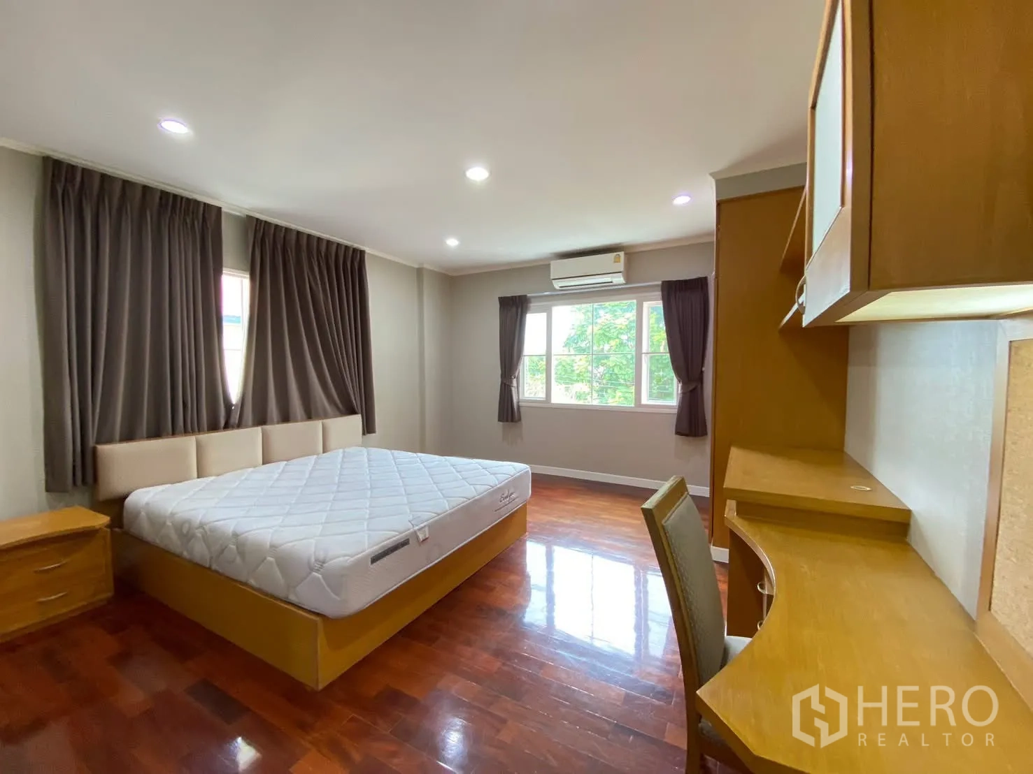 Detached House for rent in Phra Khanong, Bangkok - Spacious bedroom with large bed, built-in desk and wardrobe, air conditioning, and curtained windows.