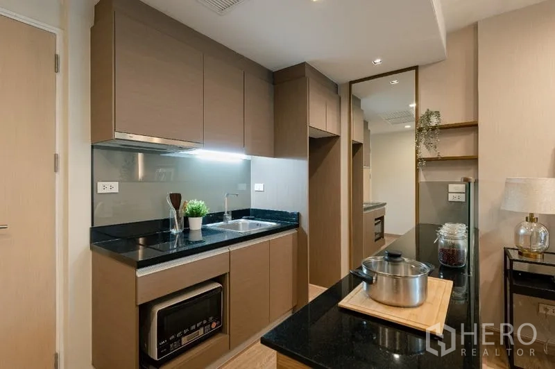 Condominium for sale - Modern kitchen with black granite countertops, sink and built-in cabinetry.