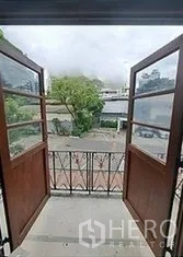 Retail Space for rent in Bangkok - Open wooden double doors lead to a small balcony with a view of a Bangkok city street.