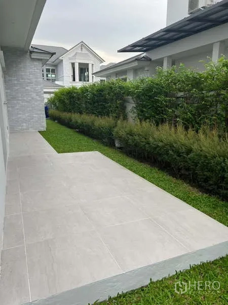 Detached House for rent or sale in Lat Krabang, Bangkok - Side terrace with tiled patio and narrow lawn bordered by hedges.