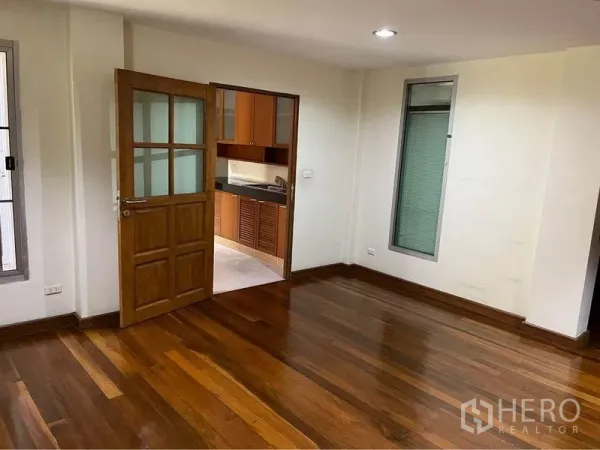 Townhouse for sale in Phra Khanong, Bangkok - Room with polished wood flooring and a doorway to a kitchen with wooden cabinetry.