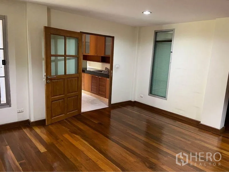 Townhouse for sale in Phra Khanong, Bangkok - Room with polished wood flooring and a doorway to a kitchen with wooden cabinetry.