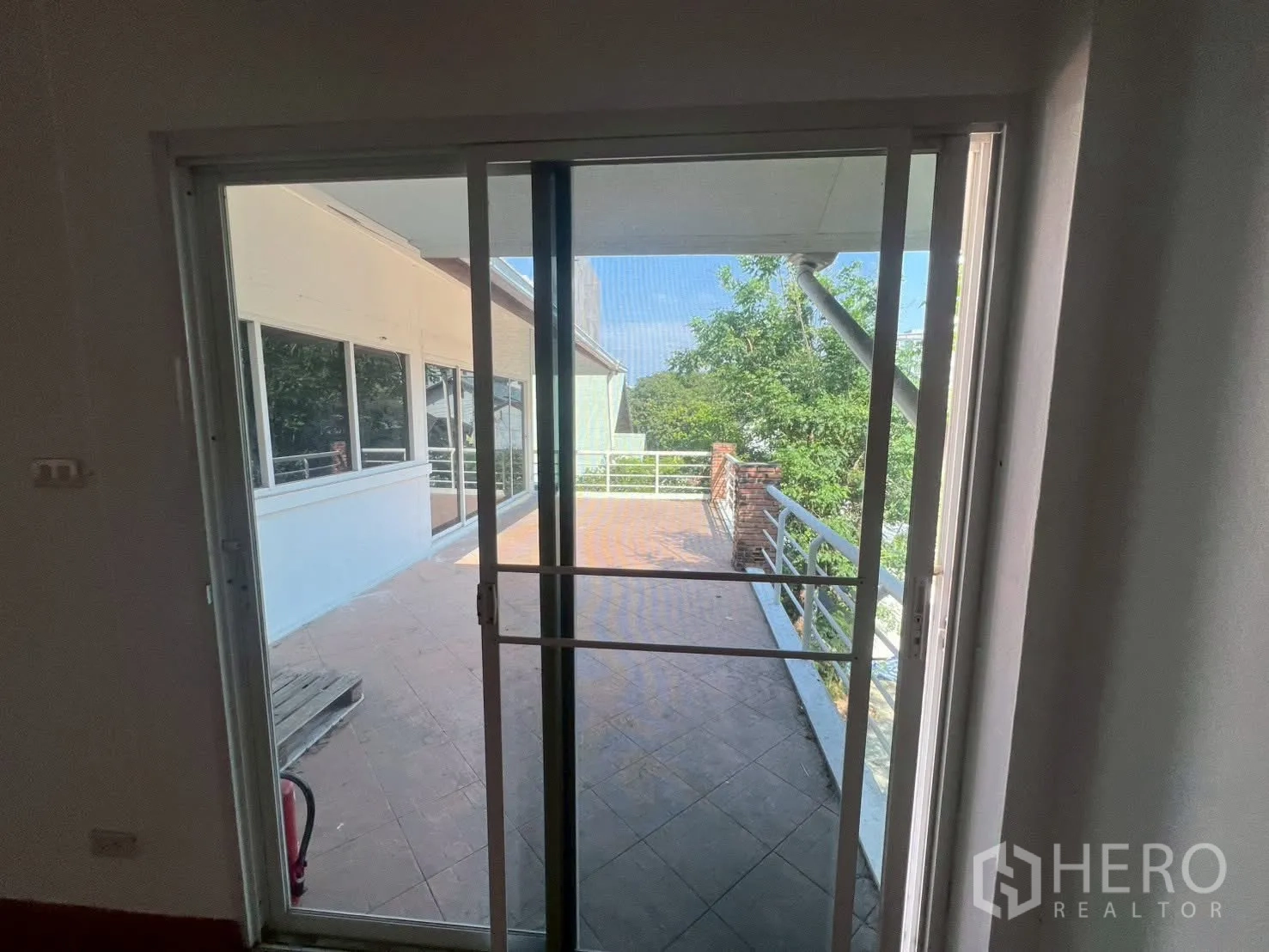 บ้านเดี่ยว for rent in Watthana, Bangkok - ประตูบานเลื่อนเปิดสู่ระเบียงกว้าง พร้อมราวกันตกและมุมมองต้นไม้