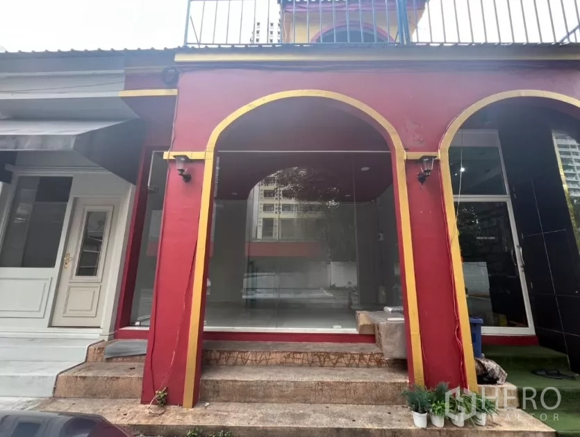 พื้นที่ขายปลีก ให้เช่าในWatthana, Bangkok - หน้าร้านกระจกพร้อมซุ้มโค้งสีแดงทองและบันไดทางเข้า