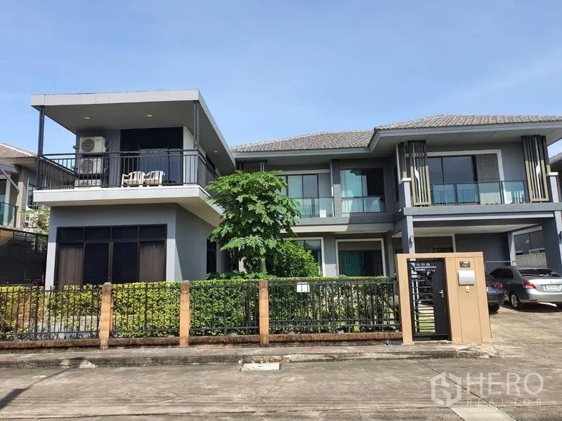 บ้าน ขายในSuan Luang, Bangkok - มุมมองด้านหน้าบ้านร่วมสมัย พร้อมระเบียงชั้นบนขนาดใหญ่ แต่งพุ่มไม้ และพื้นที่จอดรถ