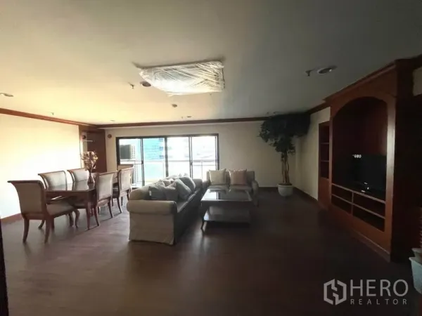 Condominium for rent in Watthana, Bangkok - Spacious living and dining area with sofa set, wooden floors, built-in TV unit and balcony windows.