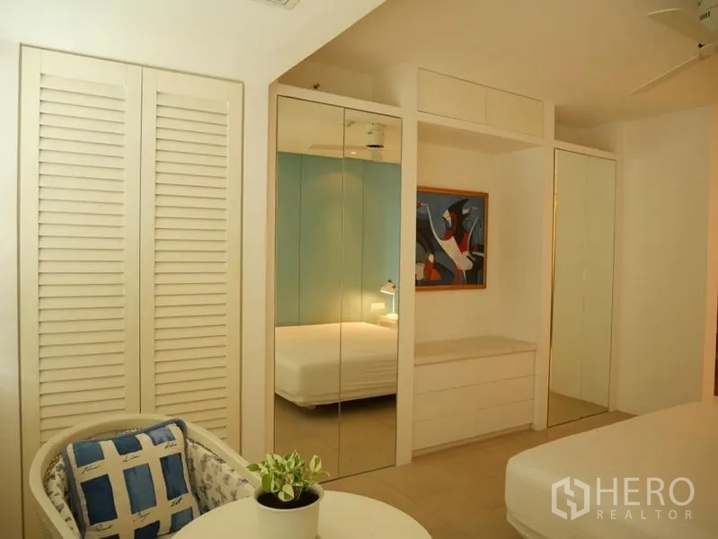Condominium for rent in Khlong Toei, Bangkok - Bedroom with mirrored wardrobes and minimalist decor.