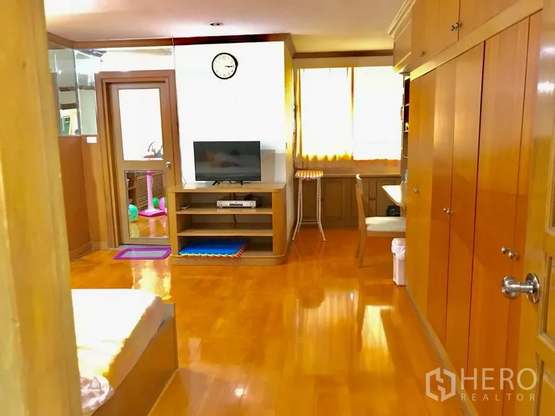 公寓 出租在Watthana, Bangkok - 宽敞多功能房，内置收纳、电视柜、书桌与木地板。