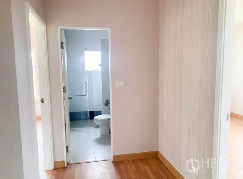 Detached House for sale in Saphan Sung, Bangkok - Hallway leading to a clean tiled bathroom with a window and glass partition.