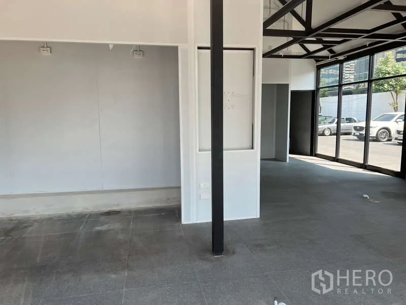 零售空间 出租 - 宽敞销售区，白色墙面、黑柱与灰色地砖。