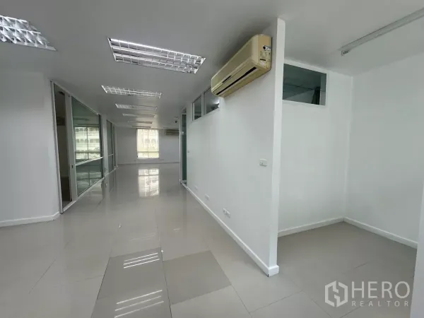 Office Space for rent in Huai Khwang, Bangkok - Bright open-plan office with glass-partitioned rooms, tiled floors, split AC units and fluorescent lighting.