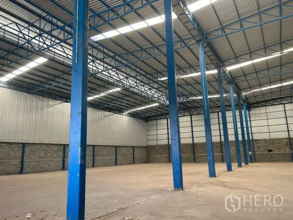 Warehouse for rent in Lat Krabang, Bangkok - Row of blue steel columns and skylights inside an industrial warehouse.