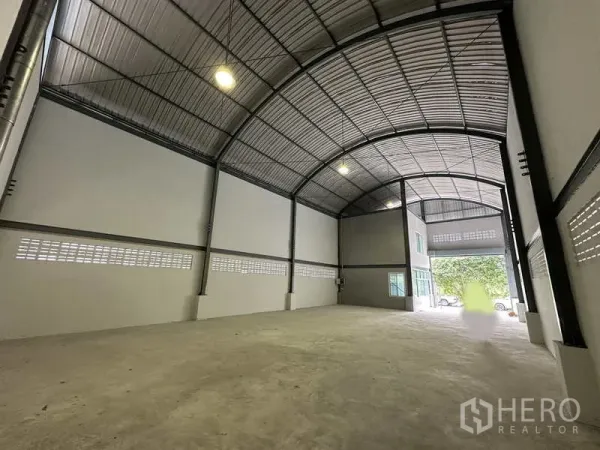 Warehouse for rent in Pak Kret, Nonthaburi - Open loading area facing the front roller door with bright overhead lighting.