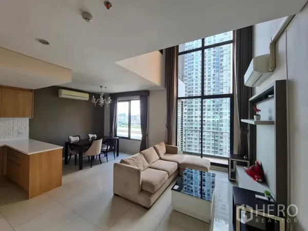 公寓 出售在Ratchathewi, Bangkok - 挑高客厅，落地窗、米色沙发、开放式厨房与城市景观