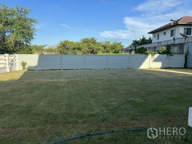 Land for sale in Prawet, Bangkok - Actual fenced land plot with level lawn and privacy walls in a quiet residential setting.