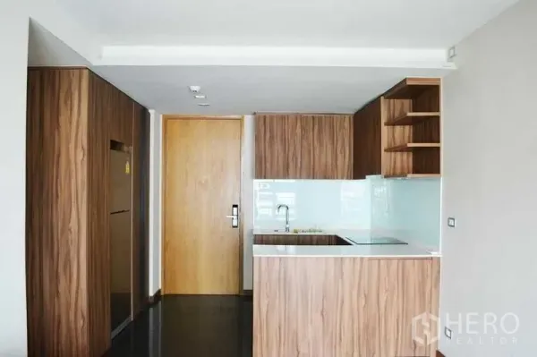 公寓 出租在Watthana, Bangkok - 曼谷公寓厨房，木纹橱柜、白色台面岛台与玻璃防溅板。