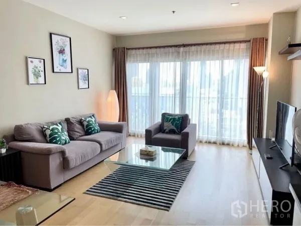 คอนโด ให้เช่าในWatthana, Bangkok - ห้องนั่งเล่นกว้าง โต๊ะกลางกระจก พรมลายทาง และหน้าต่างสูงจรดเพดาน