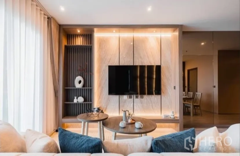 Condominium for rent in Watthana, Bangkok - Contemporary living area with built-in shelves and backlit marble TV wall.