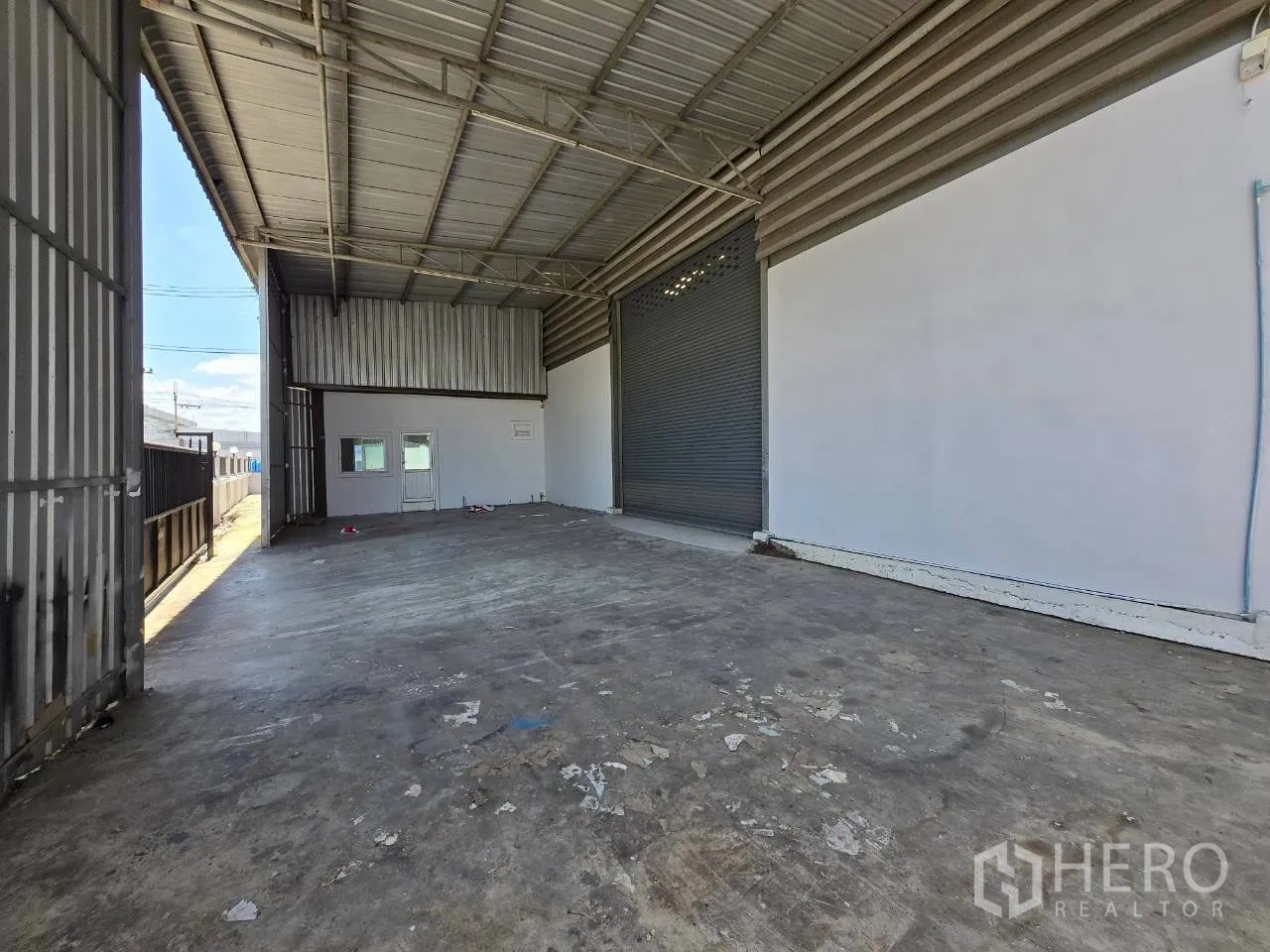 Warehouse for rent or sale in Mueang Samut Sakhon, Samut Sakhon - Sheltered loading bay with a roller shutter door and small office windows.