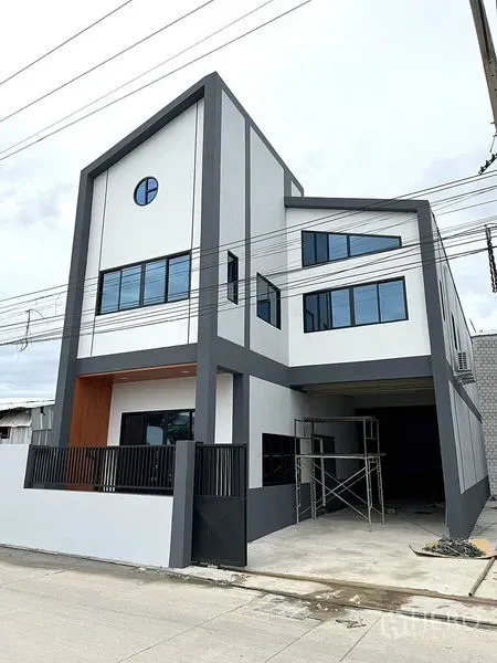 Warehouse for rent in Khlong Luang, Pathum Thani - Contemporary three-storey warehouse facade with gated driveway and large windows.