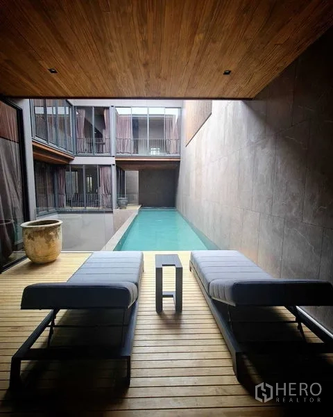 独立式住宅 出售在Lat Phrao, Bangkok - 从木质平台望向私家长条泳池，配两张躺椅与木天花。