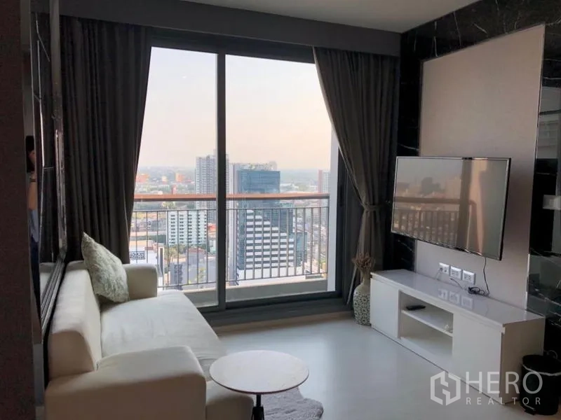 Condominium for rent in Khlong Toei, Bangkok - Living room opening to a balcony with panoramic skyline views over Ekkamai.