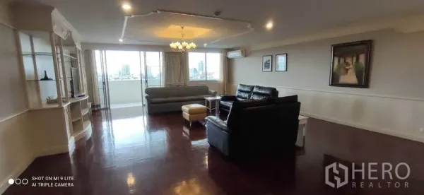 公寓 出租在Watthana, Bangkok - 客厅广角视图，吊灯、沙发与通往阳台的推门，远眺城景。
