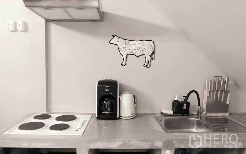 Townhouse for rent in Watthana, Bangkok - Minimal concrete kitchen with electric cooktop, sink, coffee maker and kettle.