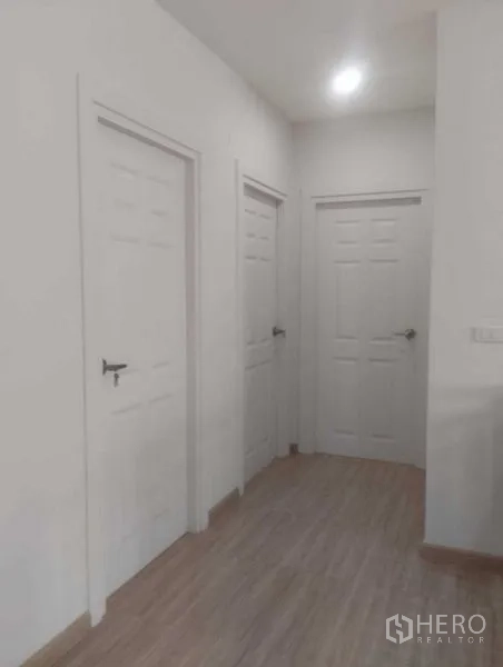 Detached House for sale in Phra Khanong, Bangkok - Bright interior hallway featuring three white doors and wood-look flooring.