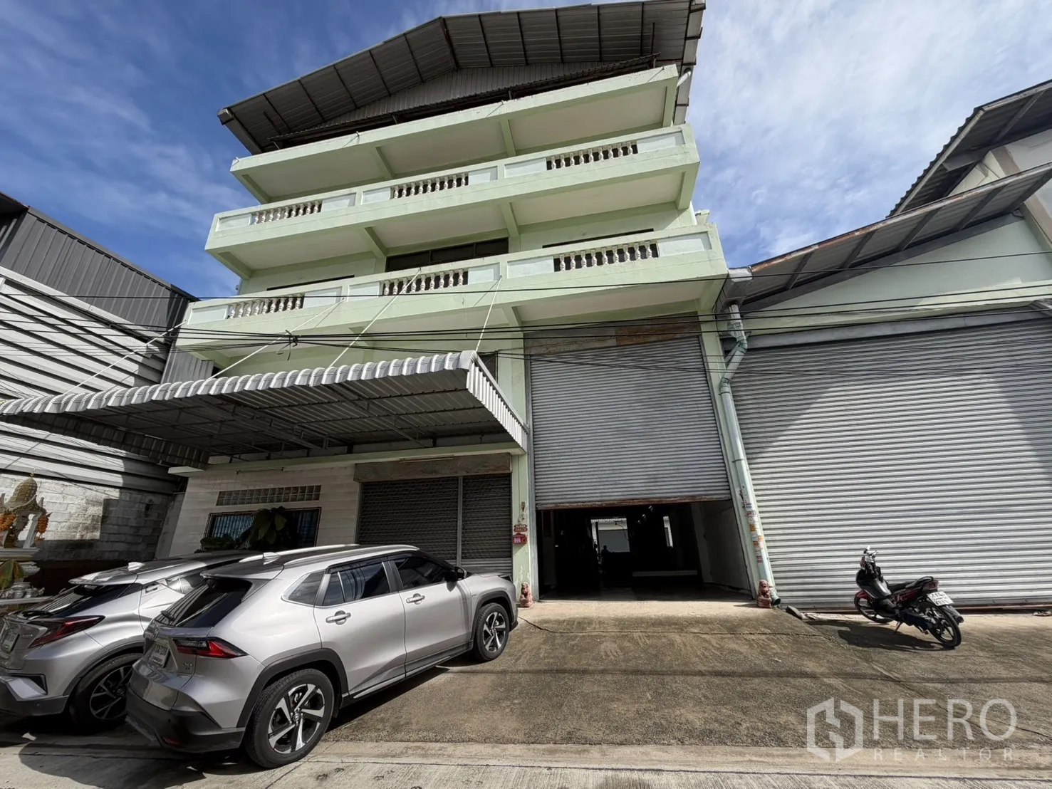 โรงงาน for rent or sale in Bang Bon, Bangkok - ด้านหน้าอาคารโรงงานหลายชั้น ประตูม้วนและที่จอดรถ