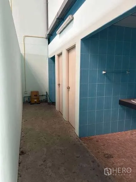 Warehouse for rent in Bang Phli, Samut Prakan - Warehouse washroom corridor with blue tiles, multiple stall doors and a sink counter.