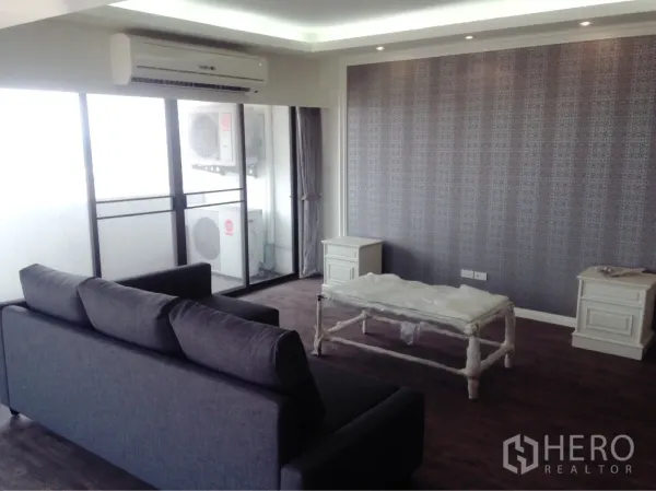 公寓 出租或出售在Chatuchak, Bangkok - 客厅设灰色沙发，推拉门通往阳台，配空调与纹理特色墙。