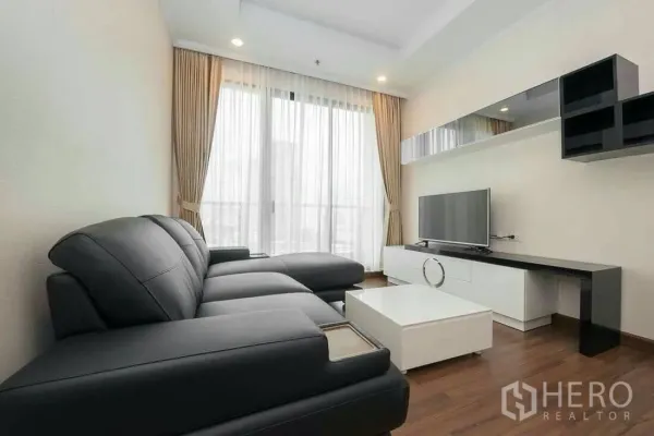 คอนโด ให้เช่าในSathon, Bangkok - ห้องนั่งเล่นโซฟาหนังสีดำ ชุดทีวี และหน้าต่างบานใหญ่พร้อมผ้าม่าน