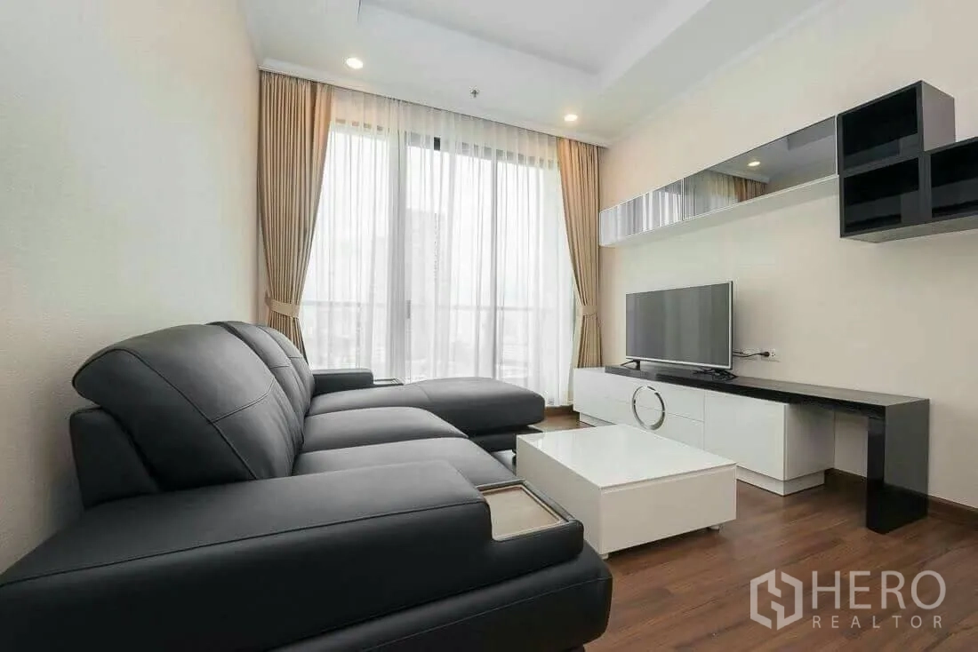 คอนโด ให้เช่าในSathon, Bangkok - ห้องนั่งเล่นโซฟาหนังสีดำ ชุดทีวี และหน้าต่างบานใหญ่พร้อมผ้าม่าน
