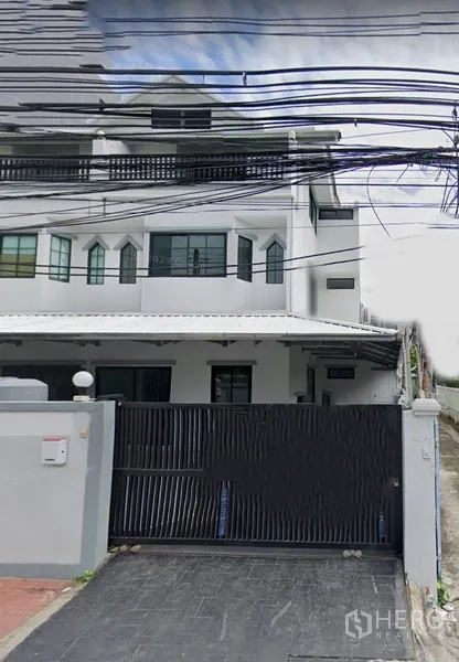 联排别墅 出租在Khlong Toei, Bangkok - 白色多层联排别墅外观，黑色滑动大门与有顶车位，深色窗框，靠近BTS娜娜站，曼谷空堤区