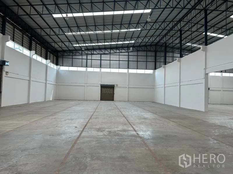 Warehouse for rent in Mueang Samut Prakan, Samut Prakan - Clear-span warehouse hall with high steel truss roof, skylights and concrete floor.