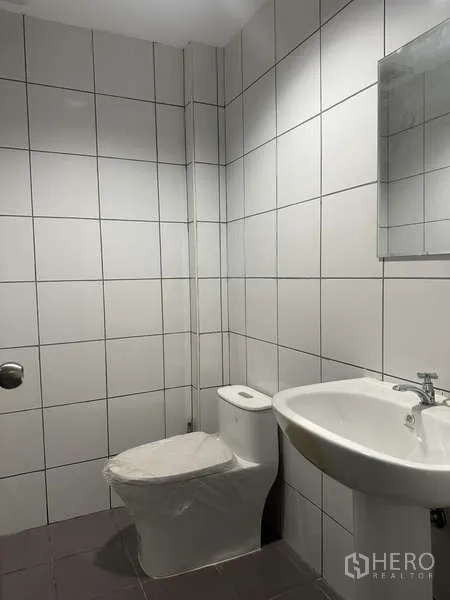 Factory for rent or sale in Bang Bua Thong, Nonthaburi - Clean tiled restroom with toilet, sink, and mirror.