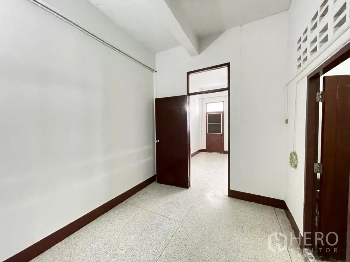 Home Office for rent in Din Daeng, Bangkok - Compact room with terrazzo floor and wooden doors, suitable as a bedroom or workspace.