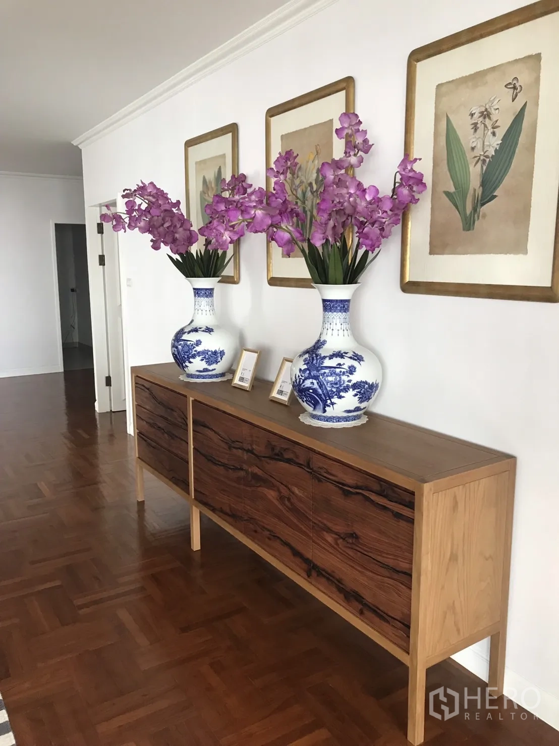 Condominium for rent in Bangkok - Hallway sideboard topped with blue-and-white vases and framed botanical artwork.