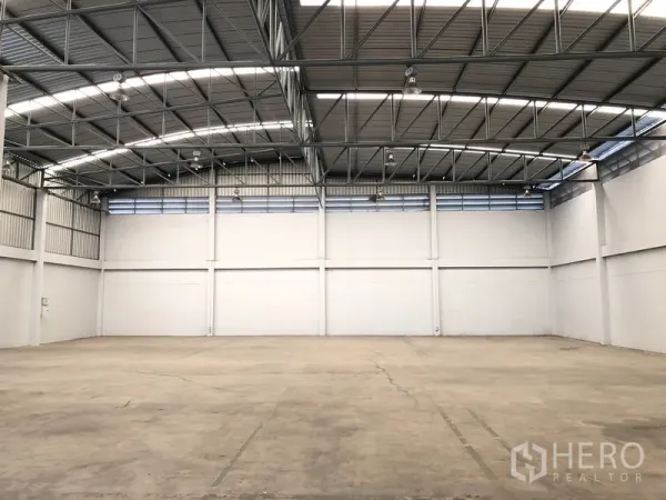 Factory for rent in Pathum Thani - Spacious warehouse hall with high steel truss roof, skylights and smooth concrete floor.
