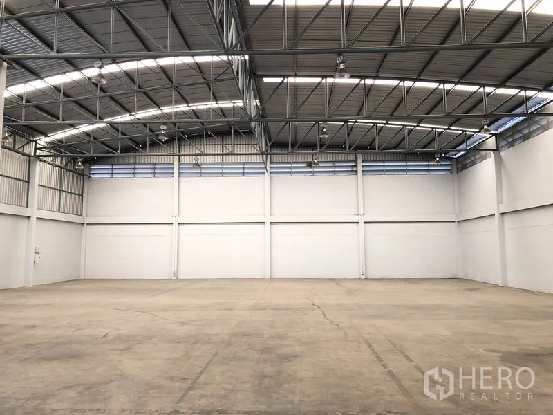 Factory for rent in Pathum Thani - Spacious warehouse hall with high steel truss roof, skylights and smooth concrete floor.