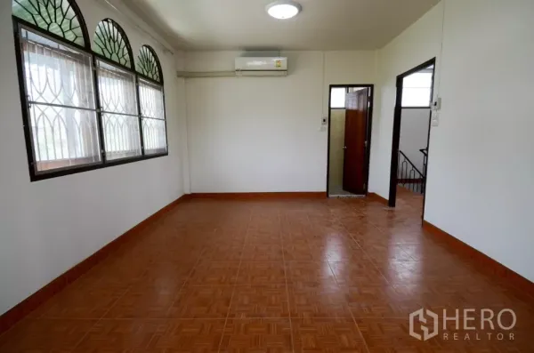 带办公室的家 出租在Lat Phrao, Bangkok - 明亮的二楼房间，拱形窗配防盗格、空调与瓷砖地面。