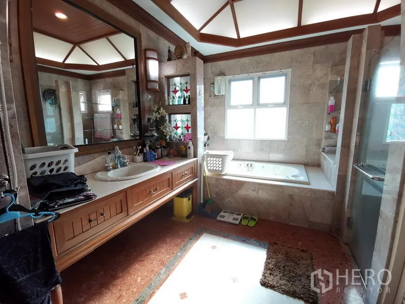 独立式住宅 出售在Phra Khanong, Bangkok - 宽敞浴室，双洗手台、临窗浴缸与独立玻璃淋浴间。